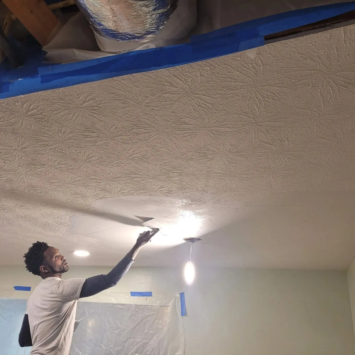 Jamaica Works crew member finishing a textured ceiling with lights