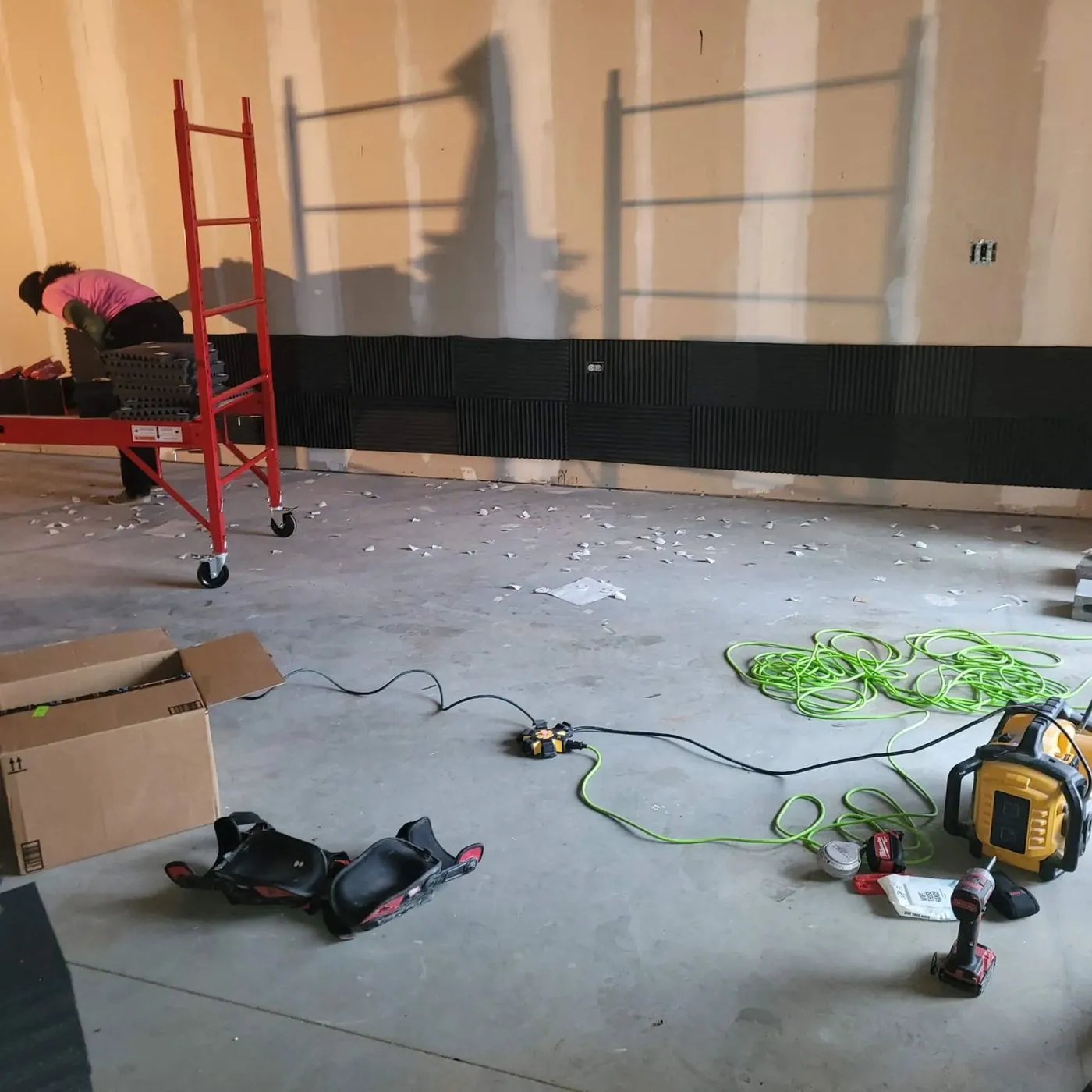Jamaica Works crew installing drywall in a commercial interior with a ladder